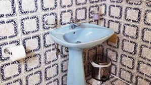 Ein Badezimmer mit gemusterten Fliesen, einem Waschbecken auf Säule und einer Toilette.