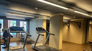 Une salle de sport équipée de tapis de course, de vélos d’exercice et d’une machine de musculation.