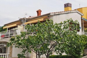 A building with a balcony, a satellite dish, and a chimney.