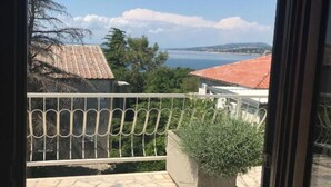 Ein Balkon mit Blick auf das Meer und die entfernten Hügel.