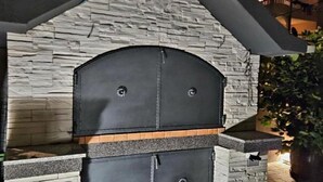 Eine Außenwand aus Stein mit einer schwarzen Grillkonstruktion.