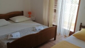 A bedroom with a wooden bed, a nightstand with a lamp, and a window with blinds.