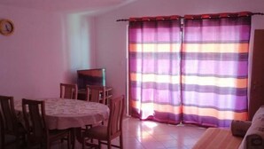A dining area with a table and chairs, a sofa, and a window with striped curtains.