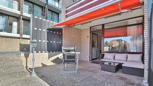 An outdoor seating area with a table and chairs, a sofa, and a large window with a view of a mountain.