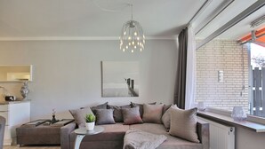 A modern living room with a sectional sofa, a small side table, a pendant light, and a view of the outside.
