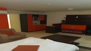 Een hotelkamer met een bed, een sofa, een kleine tafel en een kitchenette.