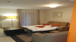 Een hotelkamer met een bed, een bank, een bureau en een lamp.