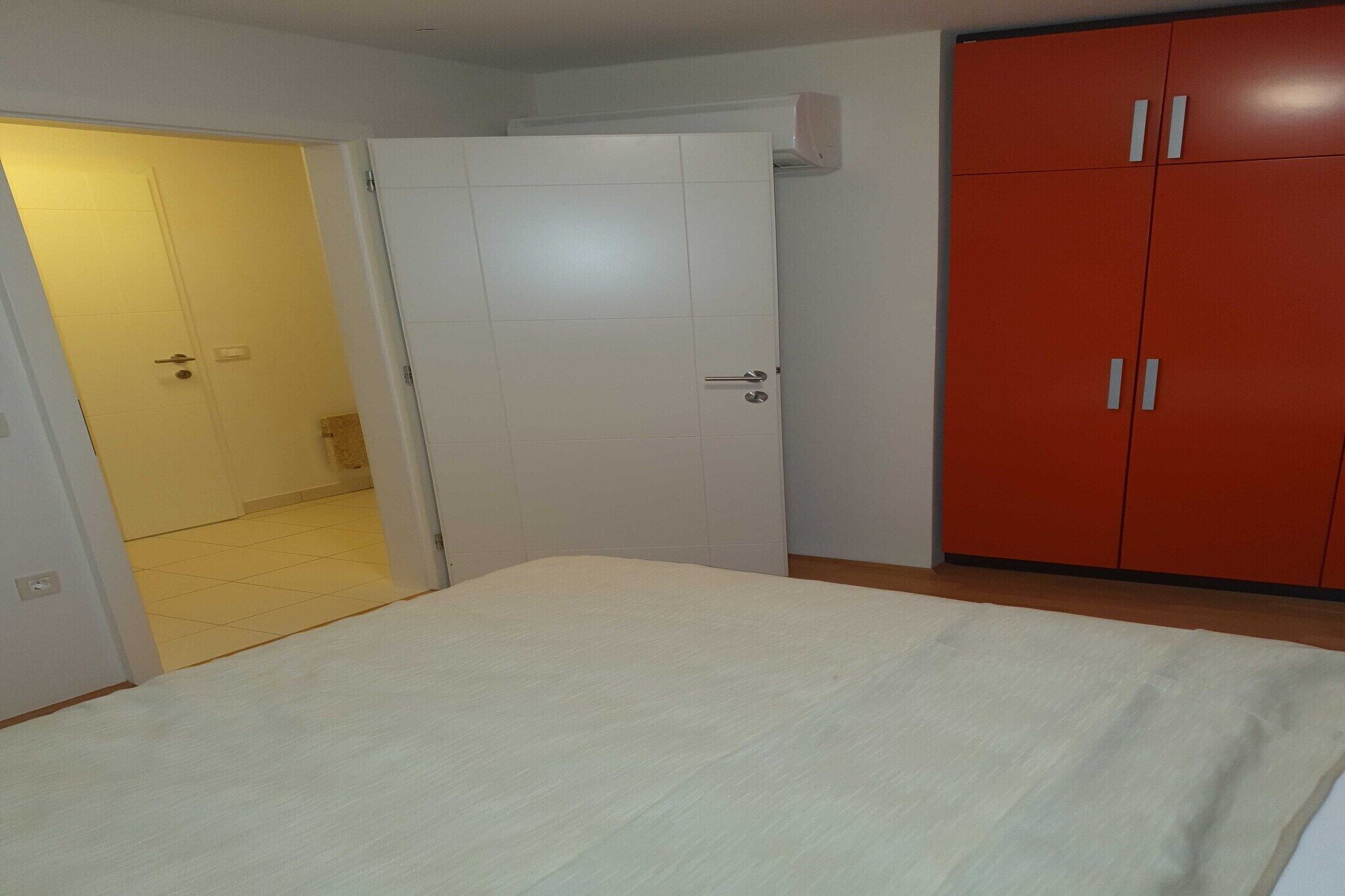 A bedroom with a bed, a wardrobe, and a door leading to another room.