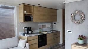 Een moderne keuken met houten kastjes, een ingebouwde magnetron en een roestvrijstalen spoelbak.