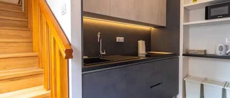 Una cocina moderna con estufa integrada, un lavamanos y un microondas en la encimera.