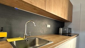 Une cuisine moderne dotée d’un évier en acier inoxydable, d’un plan de travail en bois et d’un four à micro-ondes encastré.