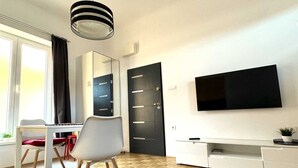 Une chambre moderne dotée d’un grand miroir, d’un téléviseur à écran plat, d’une table à manger avec des chaises et d’une porte noire.