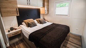 A bedroom with a bed, bedside tables, a wardrobe, a window, and a small bedside lamp.