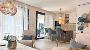 A modern living room with a sofa, chairs, a dining area, and a kitchen.