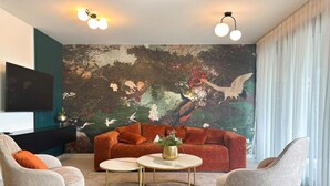 Un soggiorno moderno con un grande murale, un divano, due poltrone e un tavolino da caffè.