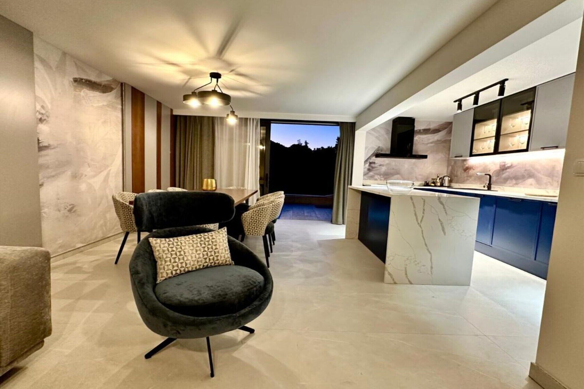 Una cocina moderna con encimeras de mármol y una silla oscura en la sala de estar.