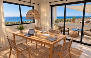 A room with a wooden table, wicker chairs, a laptop, and a view of the sea through large windows. - Luxury Seaside Villa For 8 adults! Beach & Surf-Hot Spa-Infinity Pool (Vinoramas Diamante)