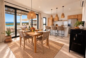 Una cocina moderna con una isla central, iluminación colgante y vistas al océano.