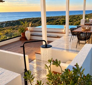 A rooftop terrace with a water feature, seating area, and a view of the ocean.