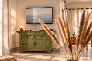 Una habitación con un armario verde, un televisor montado en la pared y una planta en maceta.