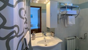 A bathroom with a white sink, a mirror, a towel rack, and a shower area. - Double room with double bed 1 (Rakovica)