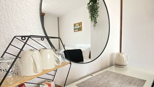 A room with a round mirror, a coffee table, a plant, and a shelf with mugs and a coffee maker. - Double room with double bed 2 (Rakovica)