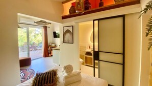 Ein Schlafzimmer mit Bett, Fernseher, Bad und Blick ins Freie.