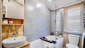 Une salle de bain moderne avec une baignoire sur pieds, des toilettes blanches et un grand miroir.