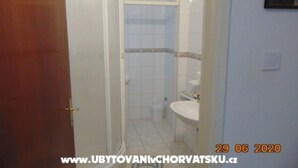 A bathroom with a white sink, a mirror, and a shower enclosure. - Three-Bedroom Apartment (Seget Donji)