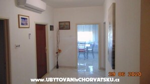 A hallway with an air conditioning unit, a wooden door, and a framed picture on the wall. - Three-Bedroom Apartment (Seget Donji)