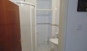 A bathroom with a white sink, a mirror, and a shower enclosure.