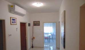 A hallway with an air conditioning unit, a wooden door, and a framed picture on the wall.
