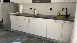 A modern kitchen with white cabinets, a stainless steel refrigerator, a black countertop, and a sink with a faucet. - Apartments Stone House Murter - Two Bedroom Apartment (Murter)