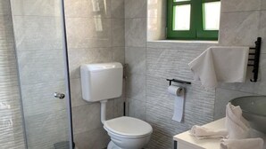 A modern bathroom with a glass shower enclosure, a toilet, and a sink area with towels. - Apartments Stone House Murter - Two Bedroom Apartment (Murter)