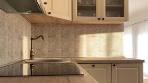 Een keuken met patroontegels, een spoelbak met een messing kraan en lichtkleurige kastjes.