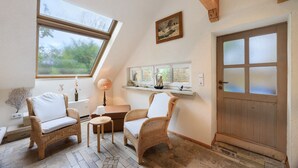 Une pièce chaleureuse avec un plafond en pente, une porte en bois et une fenêtre donnant sur un paysage verdoyant.