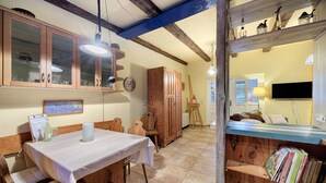 Un coin repas avec une table et des bancs en bois, un buffet en bois doté de portes en verre et une bibliothèque remplie de livres.
