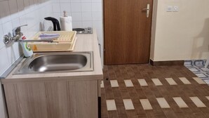 Een keuken met een spoelbak, een houten kast, een handdoekhouder en een deur.