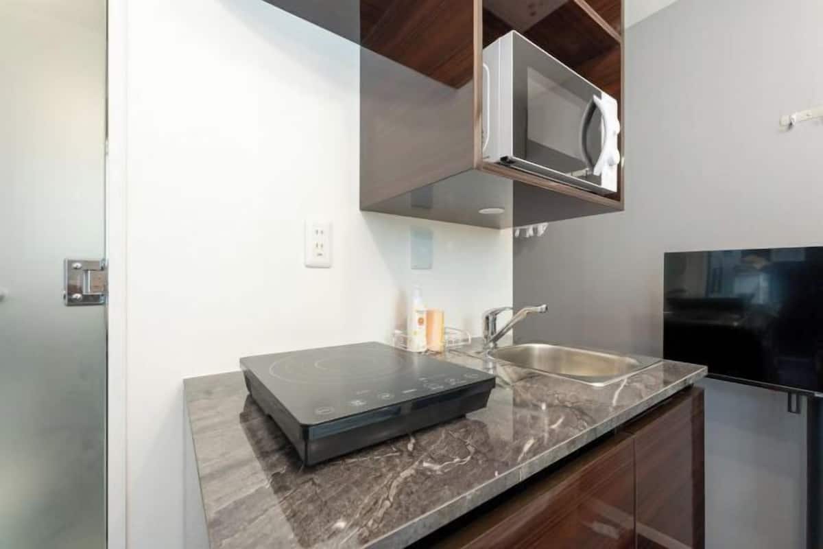 A kitchen with a built-in induction cooktop, stainless steel sink, and a microwave.