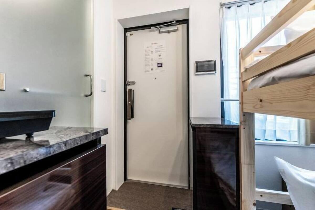 A bathroom with a sink, mirror, and wooden bunk bed.