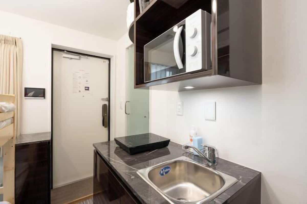 A compact kitchen with a built-in microwave, a stainless steel sink, and a small countertop.