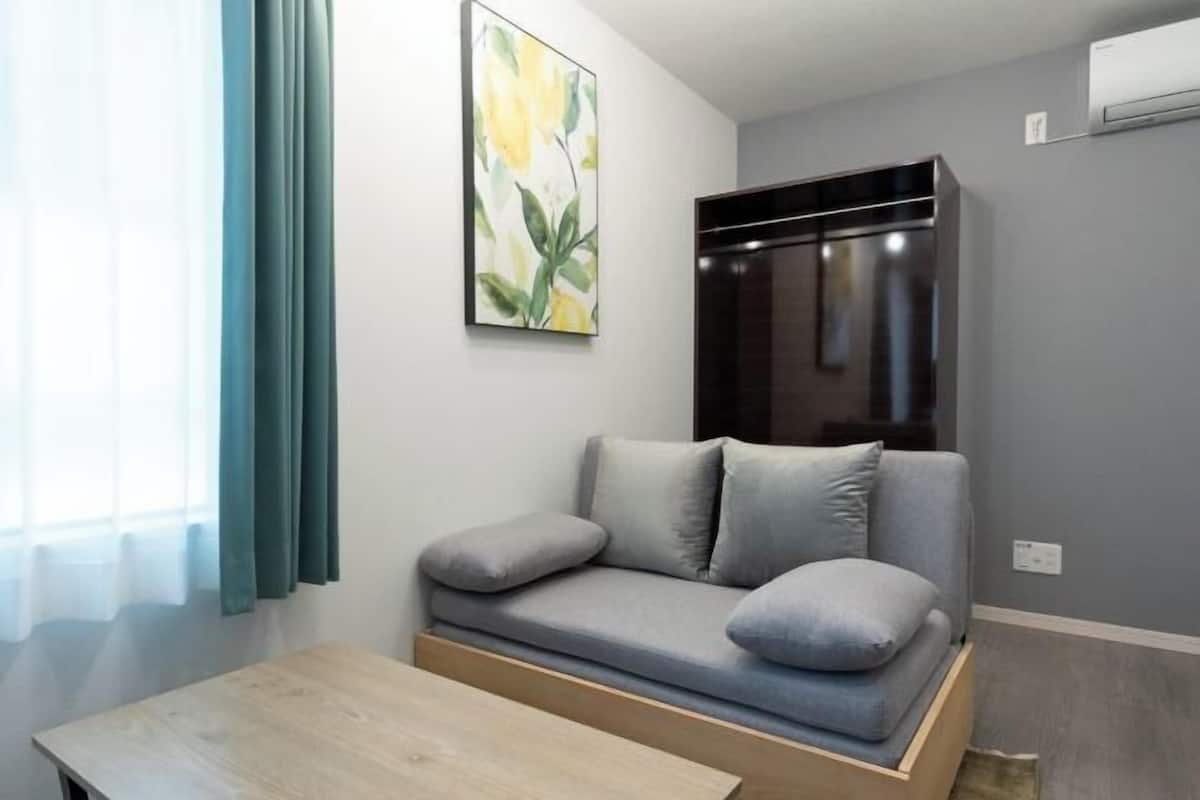 A modern room with a grey sofa, a wooden table, and a painting on the wall.