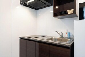 Una cucina moderna con lavello in acciaio inossidabile, mobili in legno scuro e cappa aspirante nera.