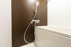 Un bagno con una doccetta, un water e un porta asciugamani a parete.