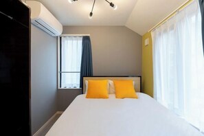Habitación de hotel con cama, ventana con cortinas, equipo de aire acondicionado y lámpara en el techo.
