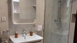A modern bathroom with a glass-enclosed shower, a white vanity with a mirror, and a small towel rack. - Goha Addis Hotel (Addis Ababa)