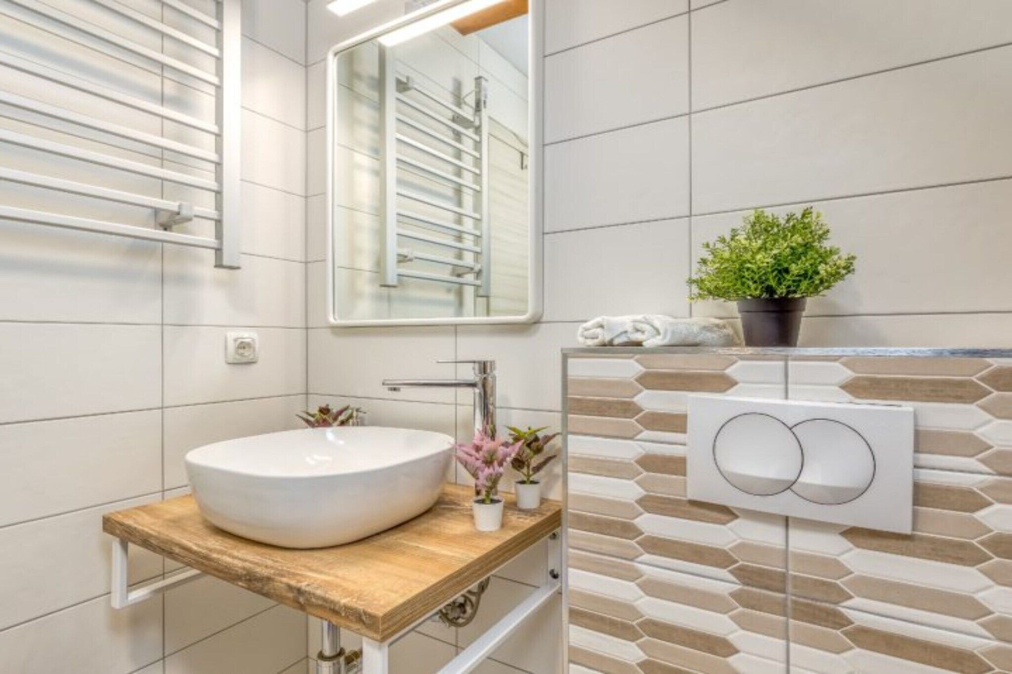 A modern bathroom with a large mirror, a round sink, and a towel rack.