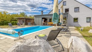 Uma casa moderna com piscina, área de estar externa e um grande guarda-sol.
