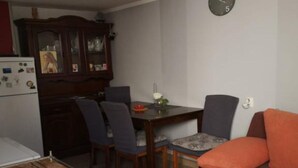 Um espaço compacto com mesa de jantar, cadeiras, sofá, relógio e geladeira.