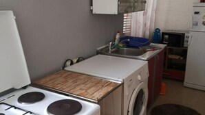 Uma cozinha compacta com fogão, pia e máquina de lavar.